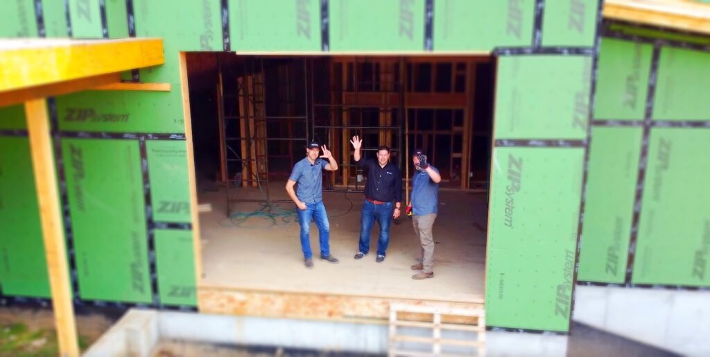 three guys standing inside a construction site wave at drone camera | P-Tn